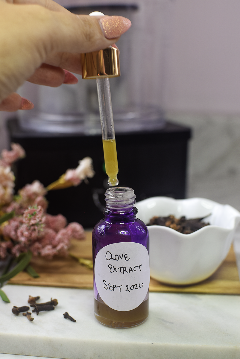 Dropper of homemade clove extract being dispensed from a glass bottle